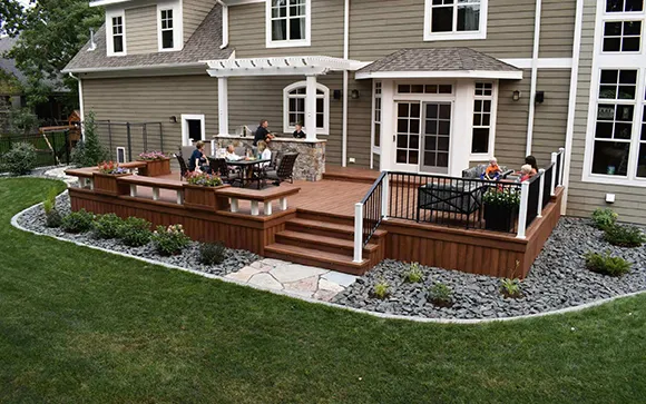 Suburban home backyard with a wooden deck, patio furniture, and a well-maintained green lawn.