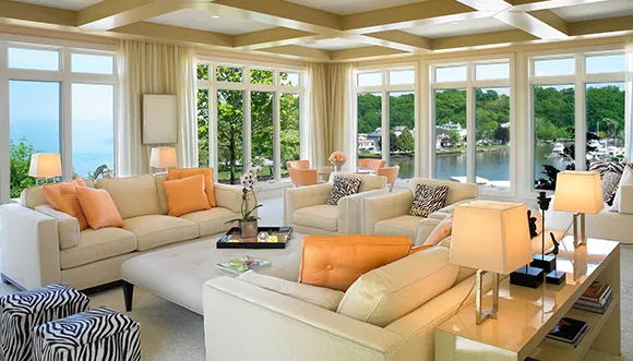 Spacious living room with large windows, modern furniture, and a cozy seating arrangement overlooking a green outdoor area.